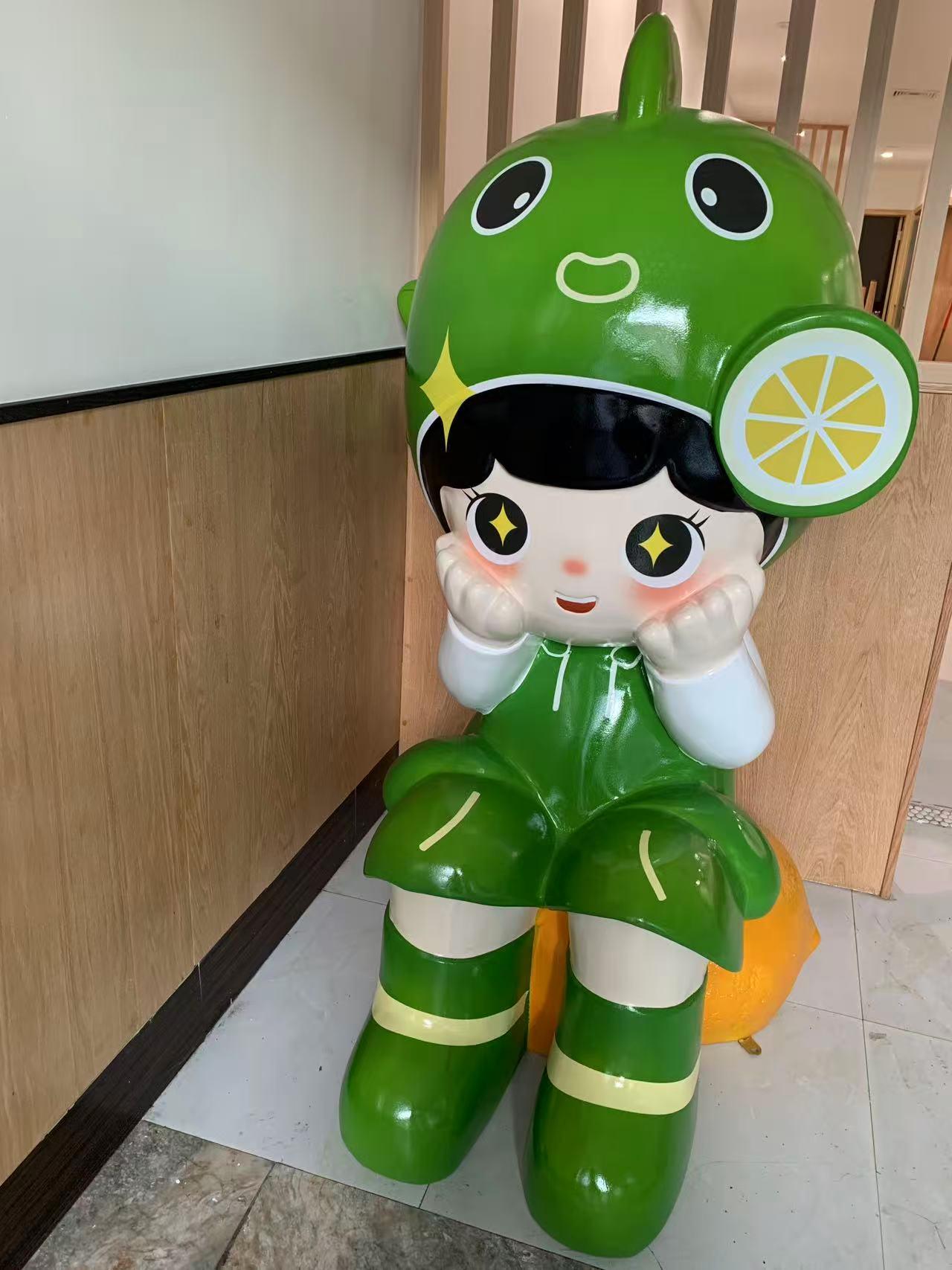 A large, green, cartoonish mascot statue with a lemon slice on its head, sitting in the corner of a restaurant.